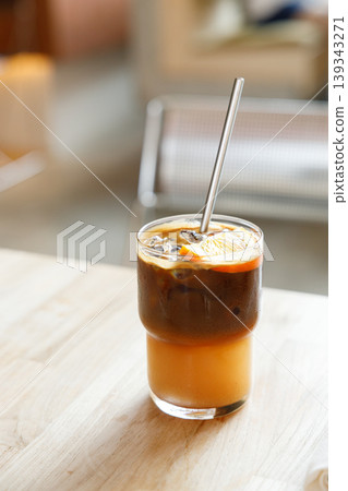 Cup of creation black coffee drink and orange juice on wooden table by the window. Cup of creation black coffee drink and orange juice on wooden table by the window. 139343271
