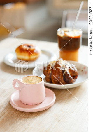 hot milk latte coffee and creation black coffee drink and orange juice with croissant on wooden table by the window. hot milk latte coffee and creation black coffee drink and orange juice with croissant on wooden table by the window. 139343274