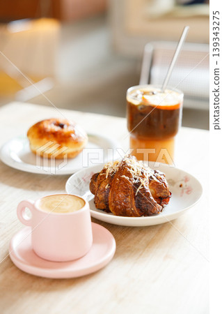 hot milk latte coffee and creation black coffee drink and orange juice with croissant on wooden table by the window. hot milk latte coffee and creation black coffee drink and orange juice with croissant on wooden table by the window. 139343275