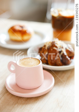 hot milk latte coffee and creation black coffee drink and orange juice with croissant on wooden table by the window. hot milk latte coffee and creation black coffee drink and orange juice with croissant on wooden table by the window. 139343276