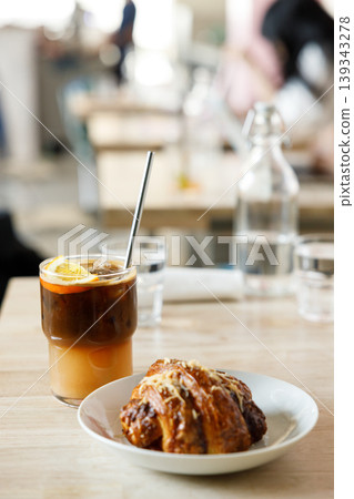 Cup of creation black coffee drink and orange juice with croissant on wooden table by the window. Cup of creation black coffee drink and orange juice with croissant on wooden table by the window. 139343278