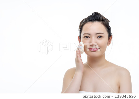 A beauty image of a young woman applying makeup with a puff. A beauty image of a young woman applying makeup with a puff. 139343650