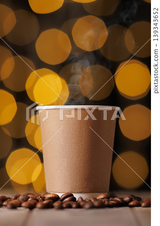 Steaming hot coffee in a blank craft paper cup on a light wooden table with scattered roasted beans, warm cozy bokeh lights evoking morning aroma and takeaway branding space Steaming hot coffee in a blank craft paper cup on a light wooden table with scattered roasted beans, warm cozy bokeh lights evoking morning aroma and takeaway branding space 139343652