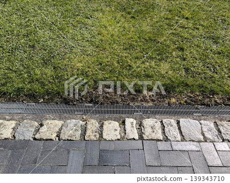 Drainage grate between the lawn and the pavement Drainage grate between the lawn and the pavement 139343710