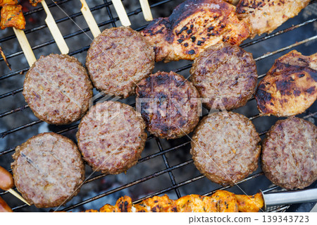 Variety of grilled meat, burgers, sausages and corn on barbecue grill outdoors, summer BBQ food cooking concept Variety of grilled meat, burgers, sausages and corn on barbecue grill outdoors, summer BBQ food cooking concept 139343723