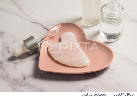 Rose quartz gua sha tool and oil bottle, face massage tool, beauty abstract photo. Copy space Rose quartz gua sha tool and oil bottle, face massage tool, beauty abstract photo. Copy space 139343966