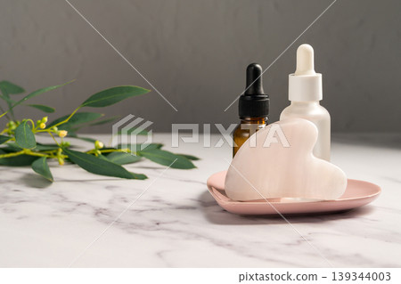 Rose quartz gua sha and oil bottles, abstract beauty photo, copy space Rose quartz gua sha and oil bottles, abstract beauty photo, copy space 139344003