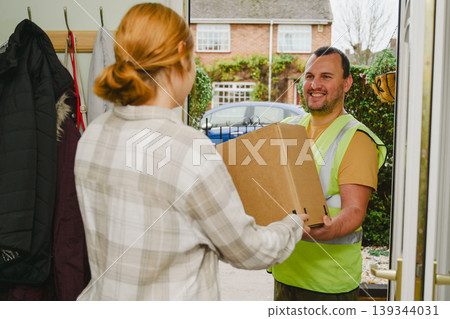 Delivery man at door entrance giving a box to a woman. Online shopping, delivery service 139344031