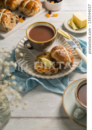 Easter food table setting. Cross Buns with butter, served with tea. Breakfast concept Easter food table setting. Cross Buns with butter, served with tea. Breakfast concept 139344037