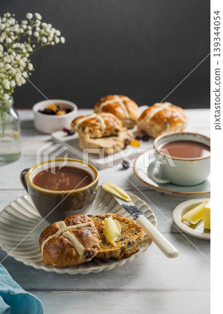 Easter food table setting. Cross Buns with butter, served with tea. Breakfast concept Easter food table setting. Cross Buns with butter, served with tea. Breakfast concept 139344054