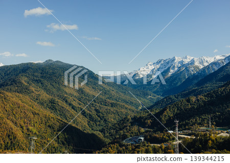 Snow-capped mountains and green valleys under blue sky in Sochi region 139344215