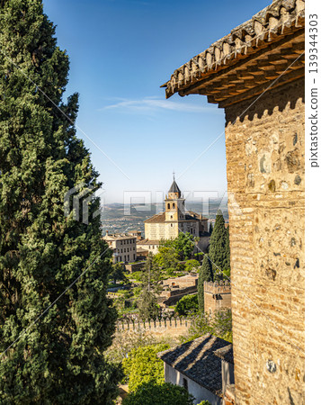 Alhambra Tower and Gardens Framed by Cypress Trees and Stone Walls in Granada, Spain Alhambra Tower and Gardens Framed by Cypress Trees and Stone Walls in Granada, Spain 139344303