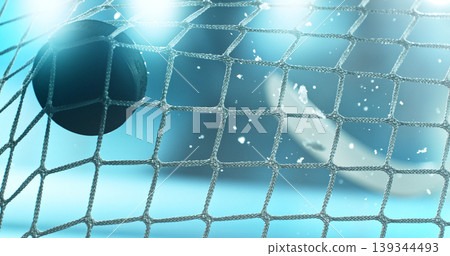 Action sports photo of a hockey puck flying into the goal net during a scoring shot, with ice particles in the air and a hockey stick visible in the background, capturing speed and intensity. Action sports photo of a hockey puck flying into the goal net during a scoring shot, with ice particles in the air and a hockey stick visible in the background, capturing speed and intensity. 139344493