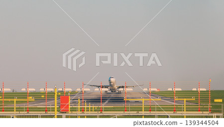 Front view of a commercial passenger airplane taking off from airport runway with visible heat haze and clear sky. Aviation, travel and transportation concept. Front view of a commercial passenger airplane taking off from airport runway with visible heat haze and clear sky. Aviation, travel and transportation concept. 139344504