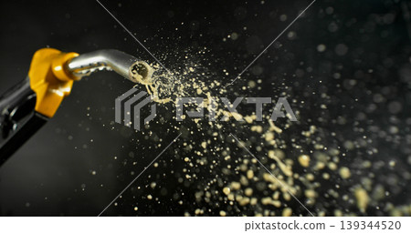 Gasoline jet spraying from fuel nozzle on dark background, no hand visible. Dynamic splash and droplets, refueling concept, energy supply, macro detail, dramatic lighting. 139344520