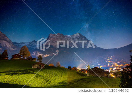 The Eiger mountain and a sky full of stars and the Milky Way stretching above a lit chalet. Grindelwald, Bern Canton, Switzerland The Eiger mountain and a sky full of stars and the Milky Way stretching above a lit chalet. Grindelwald, Bern Canton, Switzerland 139344692