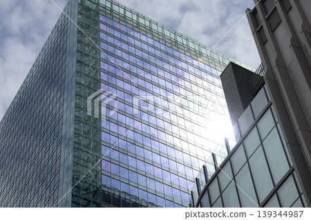 A cityscape of high-rise buildings with windows reflecting the blue sky, clouds, and sunlight. A cityscape of high-rise buildings with windows reflecting the blue sky, clouds, and sunlight. 139344987
