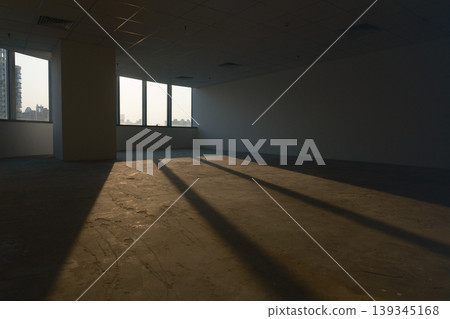 Office spaces with large windows and city views, featuring patterns of shadows cast by natural light. Office spaces with large windows and city views, featuring patterns of shadows cast by natural light. 139345168