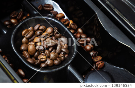 freshly roasted coffee beans within the chamber of a coffee grinder freshly roasted coffee beans within the chamber of a coffee grinder 139346584