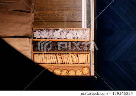 Assorted cookies and pastries in a wooden display box on a dark background with natural light Assorted cookies and pastries in a wooden display box on a dark background with natural light 139346834