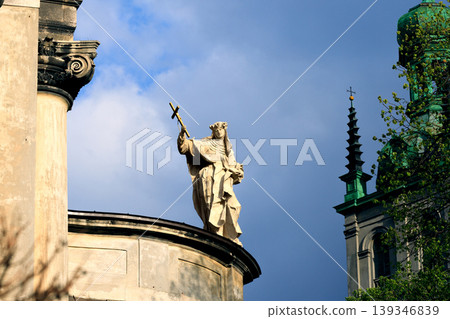 Dramatic religious sculpture atop a historic European cathedral dome under overcast skies Dramatic religious sculpture atop a historic European cathedral dome under overcast skies 139346839