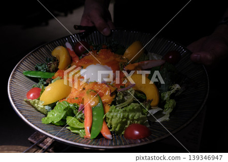 A gorgeous Japanese-style salad topped with flying fish roe, a soft-boiled egg, and mango is served in a dark bowl. A gorgeous Japanese-style salad topped with flying fish roe, a soft-boiled egg, and mango is served in a dark bowl. 139346947