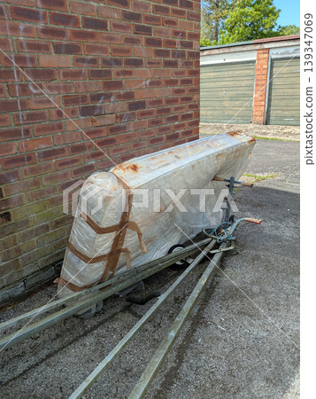 Dumped dirty mattress rotting next to a row of garages 139347069