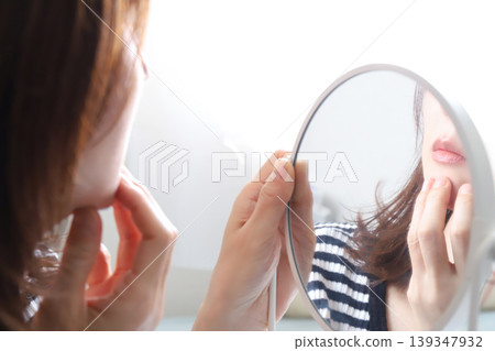 woman checking her skin in the mirror woman checking her skin in the mirror 139347932