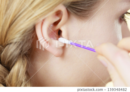 Woman cleaning ear with cotton swabs closeup Woman cleaning ear with cotton swabs closeup 139348482