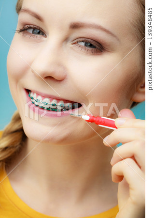 Woman with teeth braces using interdental brush Woman with teeth braces using interdental brush 139348485
