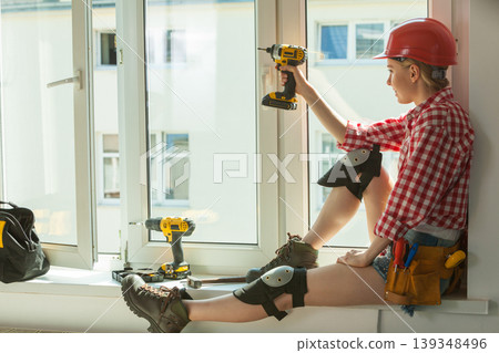 Woman using drill on window 139348496