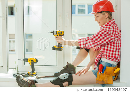 Woman using drill on window Woman using drill on window 139348497