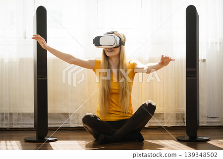 Girl wearing virtual reality goggles at home Girl wearing virtual reality goggles at home 139348502