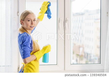 Woman cleaning window at home Woman cleaning window at home 139348504