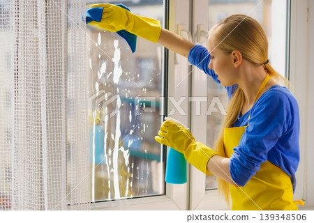 Woman cleaning window at home Woman cleaning window at home 139348506