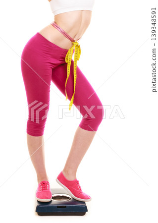 Woman with tape measure on weighing scale. Woman with tape measure on weighing scale. 139348591