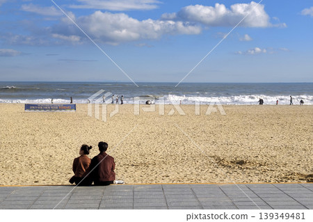 Korean couple sit at Haeundae beach in sunny day Korean couple sit at Haeundae beach in sunny day 139349481