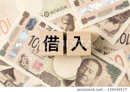 一塊寫著「借貸」字樣的磚塊和許多10,000日圓面額的鈔票。 一塊寫著「借貸」字樣的磚塊和許多10,000日圓面額的鈔票。 139349517
