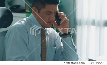Skilled engineer look at mobile phone while working on tablet. Alimentation. Skilled engineer look at mobile phone while working on tablet. Alimentation. 139349555