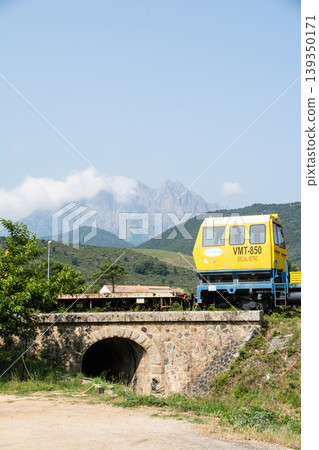 A railway inspection car and a stone bridge surrounded by mountains on the French island of Corsica in the Mediterranean Sea. A railway inspection car and a stone bridge surrounded by mountains on the French island of Corsica in the Mediterranean Sea. 139350171