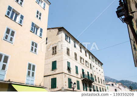 A building with cream-colored walls bathed in bright sunlight on the French island of Corsica in the Mediterranean Sea. 139350209