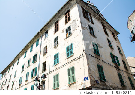 A building with cream-colored walls bathed in bright sunlight on the French island of Corsica in the Mediterranean Sea. 139350214