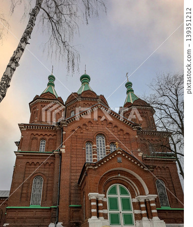 ZADONSK, Russia - April 17, 2026. Holy Trinity Cathedral in Zadonsk displays red brick walls and green domes under a soft sunset sky. The view captures the traditional Russian Orthodox architecture fr ZADONSK, Russia - April 17, 2026. Holy Trinity Cathedral in Zadonsk displays red brick walls and green domes under a soft sunset sky. The view captures the traditional Russian Orthodox architecture fr 139351212