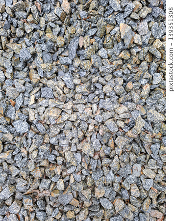 Gravel stones are shown from above, featuring a mix of grey and brown granite. This material is often used in construction and landscaping projects. Gravel stones are shown from above, featuring a mix of grey and brown granite. This material is often used in construction and landscaping projects. 139351308