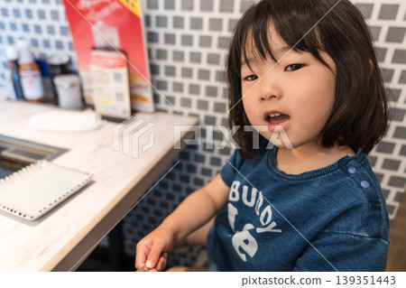 一位年輕的日本女孩坐在鐵板燒餐廳的桌旁。 139351443