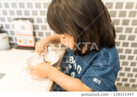 A young Japanese girl sitting at a table in a teppanyaki restaurant. A young Japanese girl sitting at a table in a teppanyaki restaurant. 139351447