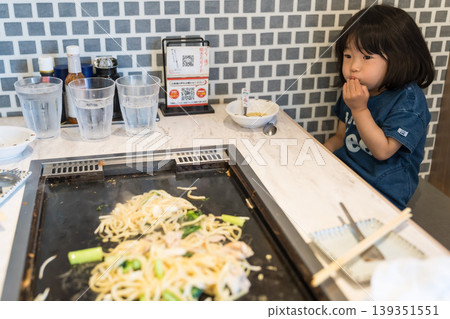 A young Japanese girl eating monjayaki at a teppanyaki restaurant. 139351551