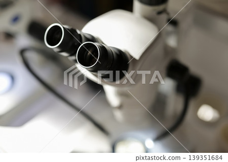Close up of a laboratory binocular microscope in use, emphasizing micro scale analysis and detailed scientific investigation. Close up of a laboratory binocular microscope in use, emphasizing micro scale analysis and detailed scientific investigation. 139351684
