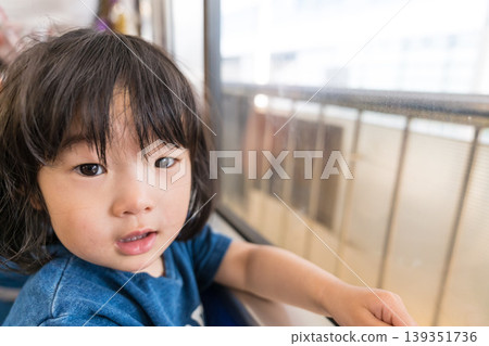 一位年輕的日本女孩正望著電車窗外。 139351736