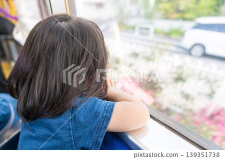 A young Japanese girl looking out the window of a streetcar. A young Japanese girl looking out the window of a streetcar. 139351738